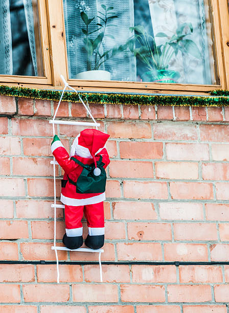 Outdoor Christmas Decoration Santa hanging on a ladder house facade